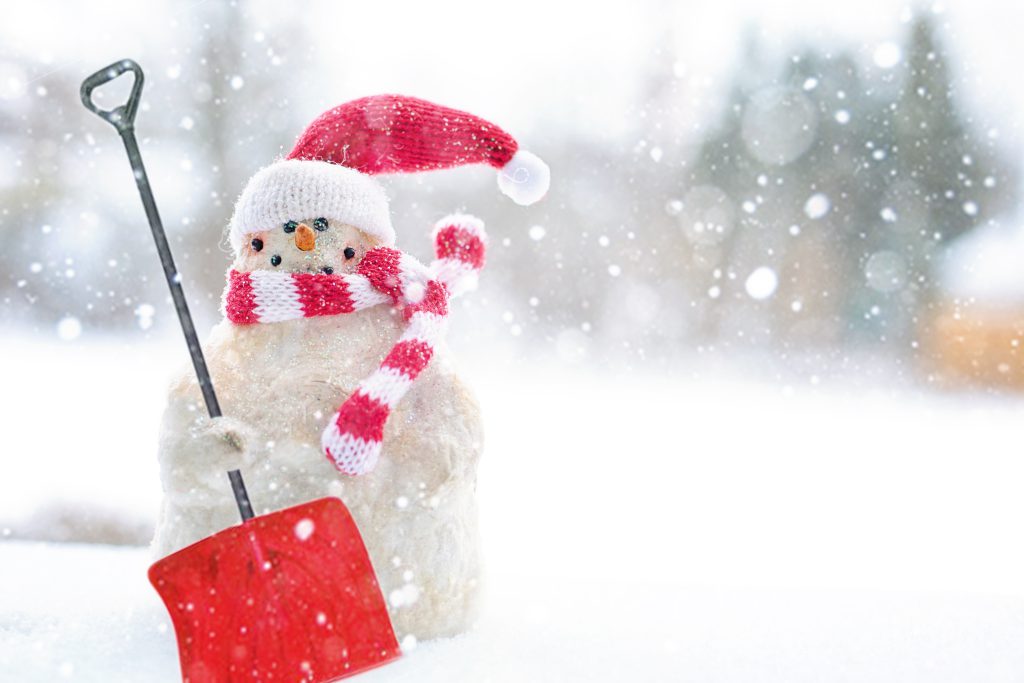 UK snowman with christmas hat and scarf. Pictured with a shovel.