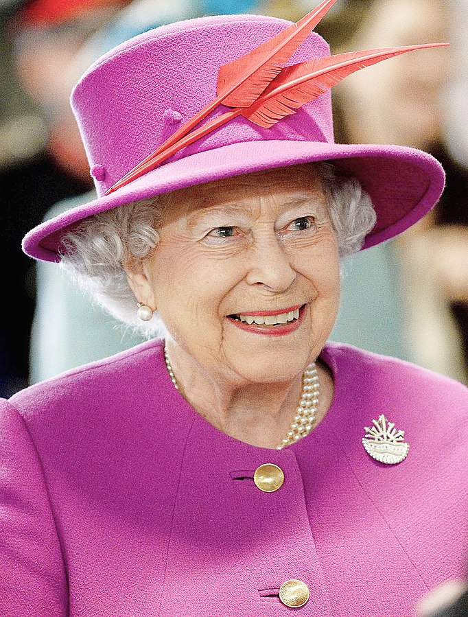 A recent photograph of Her Late Majesty the Queen. Pictured wearing a pink suit jacket and matching hat. She can be seen smiling.
A new commemorative UK coin set has been issued, including the last coins of Queen Elizabeth II, featuring a special privy mark.